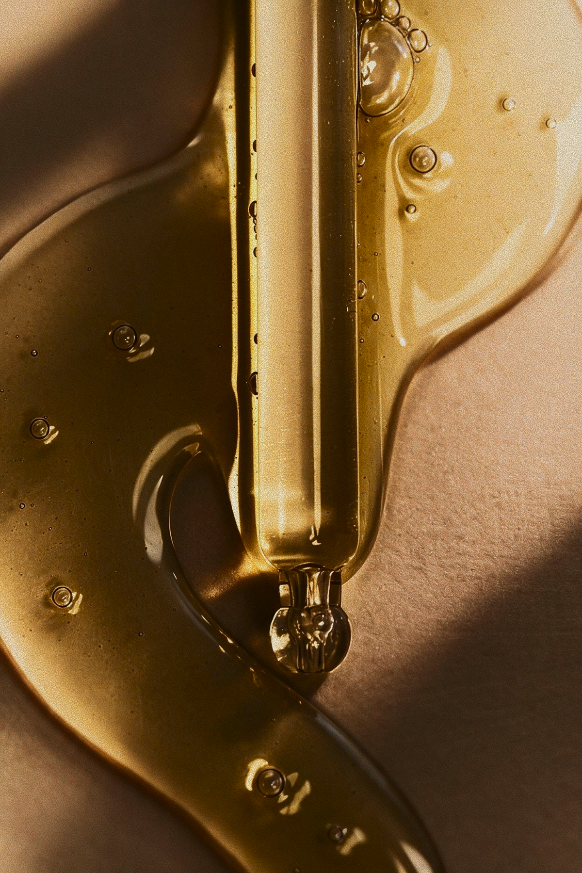 Macro shot of golden facial serum dripping from a pipette, used in the Buccal & Glow treatment at Skincuress in Hoboken, NJ