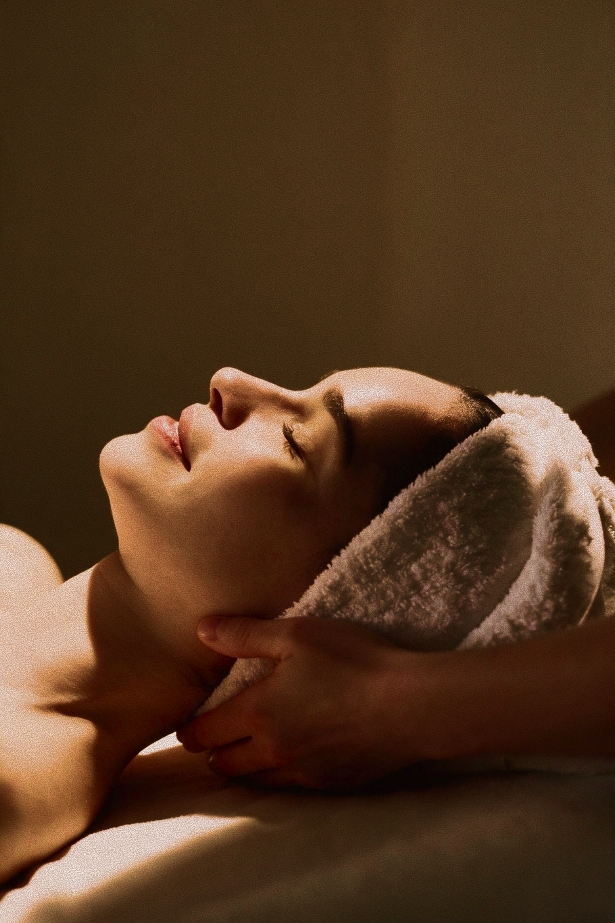 Woman relaxing with eyes closed during a neck massage as part of Skincuress's In Residence at-home spa treatment in Hoboken, NJ