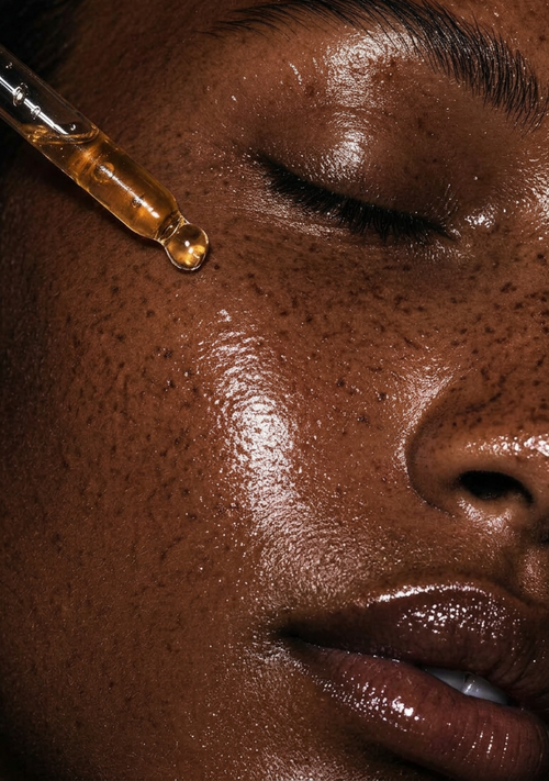 Close-up of glowing skin with a serum dropper applying treatment during the Signature Skincuress Facial in Hoboken, NJ