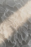 Delicate white lace fabric texture, capturing the soft, healing ambiance of the Somatic Sculpt facial at Skincuress in Hoboken, NJ